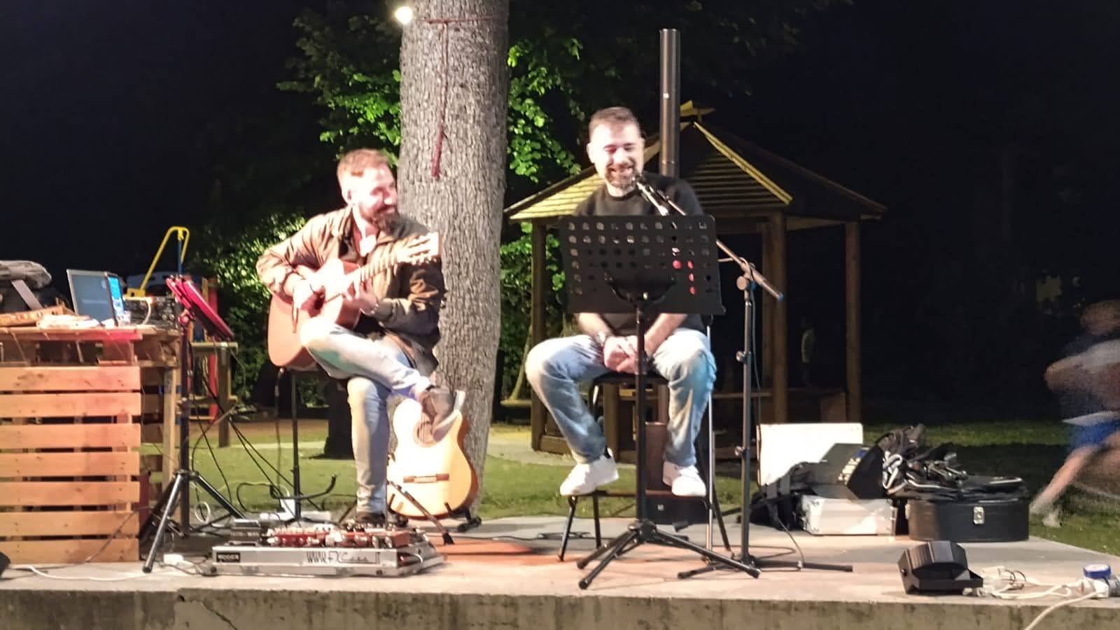 Mirko e Raffaele si esibiscono insieme all'aperto, con chitarra e microfono